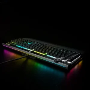 Low-angle side view of the Corsair K100 RGB keyboard in a dark room highlighting the 44-zone LightEdge and per-key RGB backlighting.