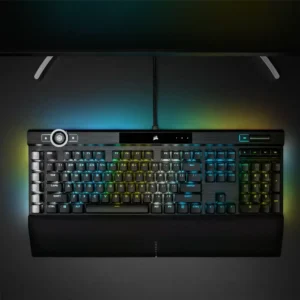 Overhead top view of the Corsair K100 RGB keyboard positioned on a desk below a monitor with full RGB illumination.