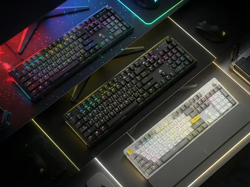 Multiple Corsair K70 Core mechanical keyboards in black and white/silver layouts featuring a multi-function rotary dial.