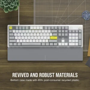 Corsair K70 Core SE keyboard on a wooden desk highlighting its 85% post-consumer recycled plastic bottom case.