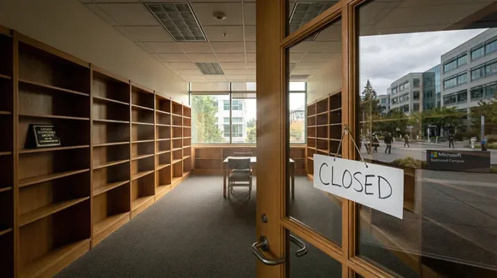 Empty wooden bookshelves in a closed corporate library reading room at the Microsoft Redmond campus, with a "Closed" sign on the door.